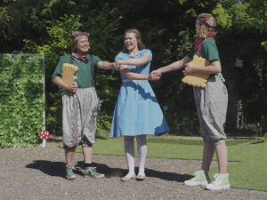 Alice hält die Hände von zwei anderen Schauspielern überkreuz