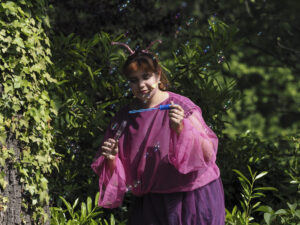 Eine Schauspielerin in einem pink lila Schmetterlingskostüm macht Seifenblasen