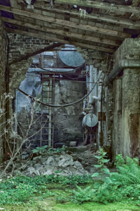 Eine Leiter und ein Tank an der Wand der alten Fabrikhalle, der gleiche Blick von etwas weiter hinten