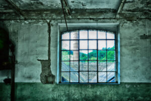 Ein Fenster mit Blick nach draußen auf einen Industrieschornstein