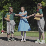 Alice hält die Hände von zwei anderen Schauspielern überkreuz