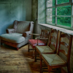 Ein Raum it drei Stühlen nebeneinander am Fenster und einem Sessel in der Zimmerecke