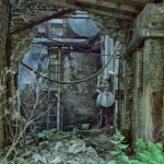 Eine Leiter und ein Tank an der Wand der alten Fabrikhalle, der gleiche Blick von etwas weiter hinten