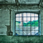 Ein Fenster mit Blick nach draußen auf einen Industrieschornstein